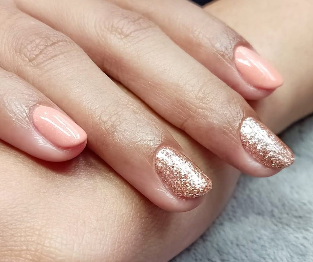 Peach pastel nails with gold glitter tips