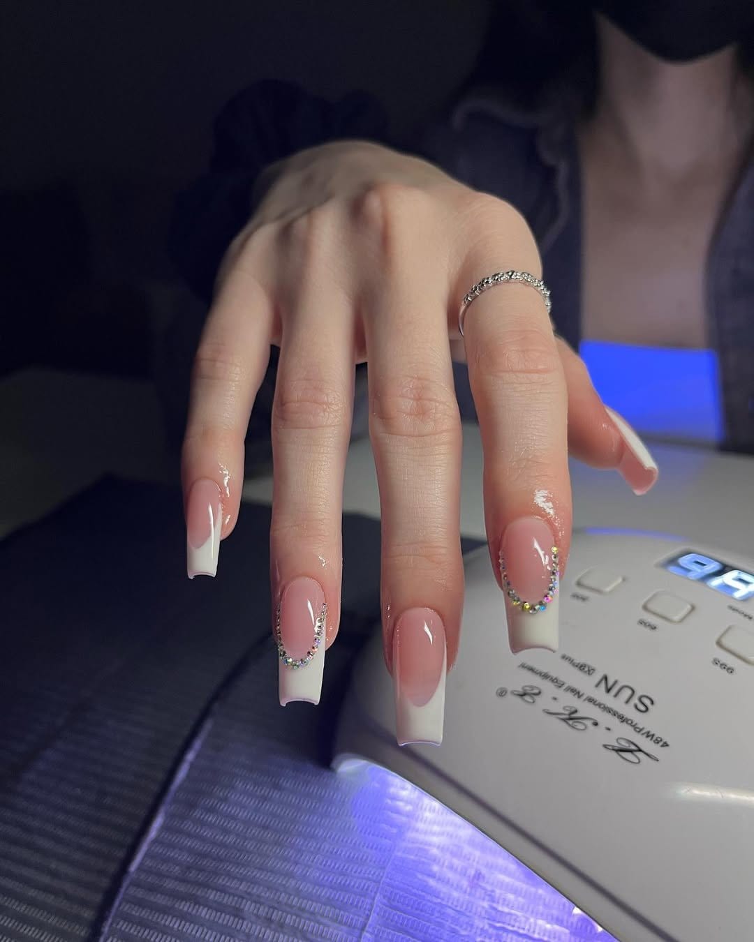 Gemstone-accented French tip nails with luxurious embellishments