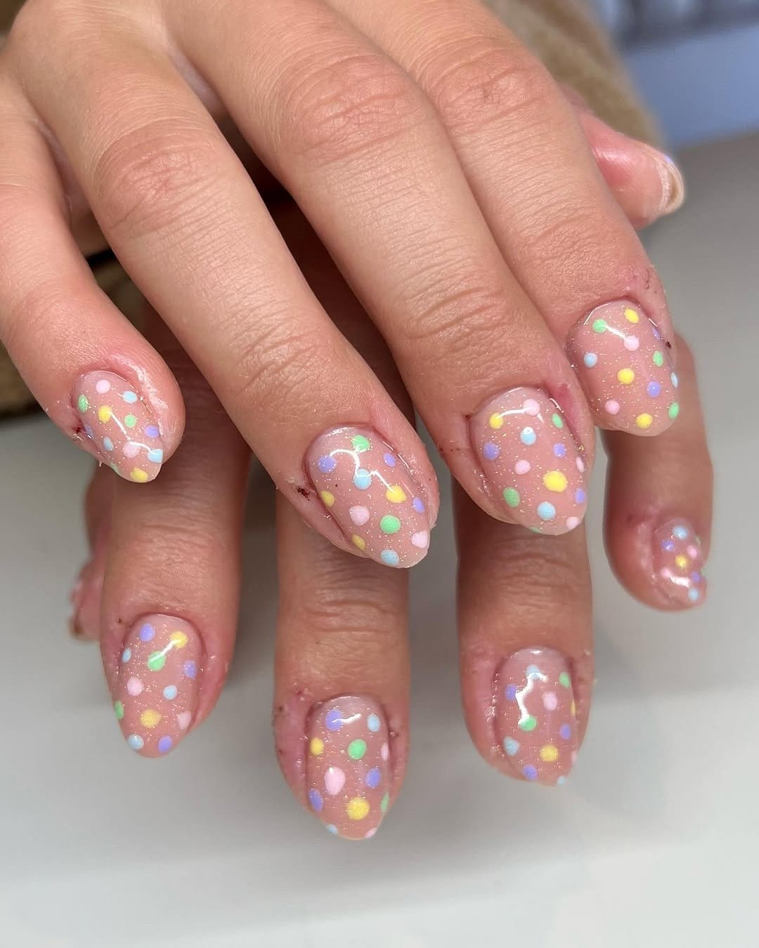 Pastel polka dot nail design on a white base