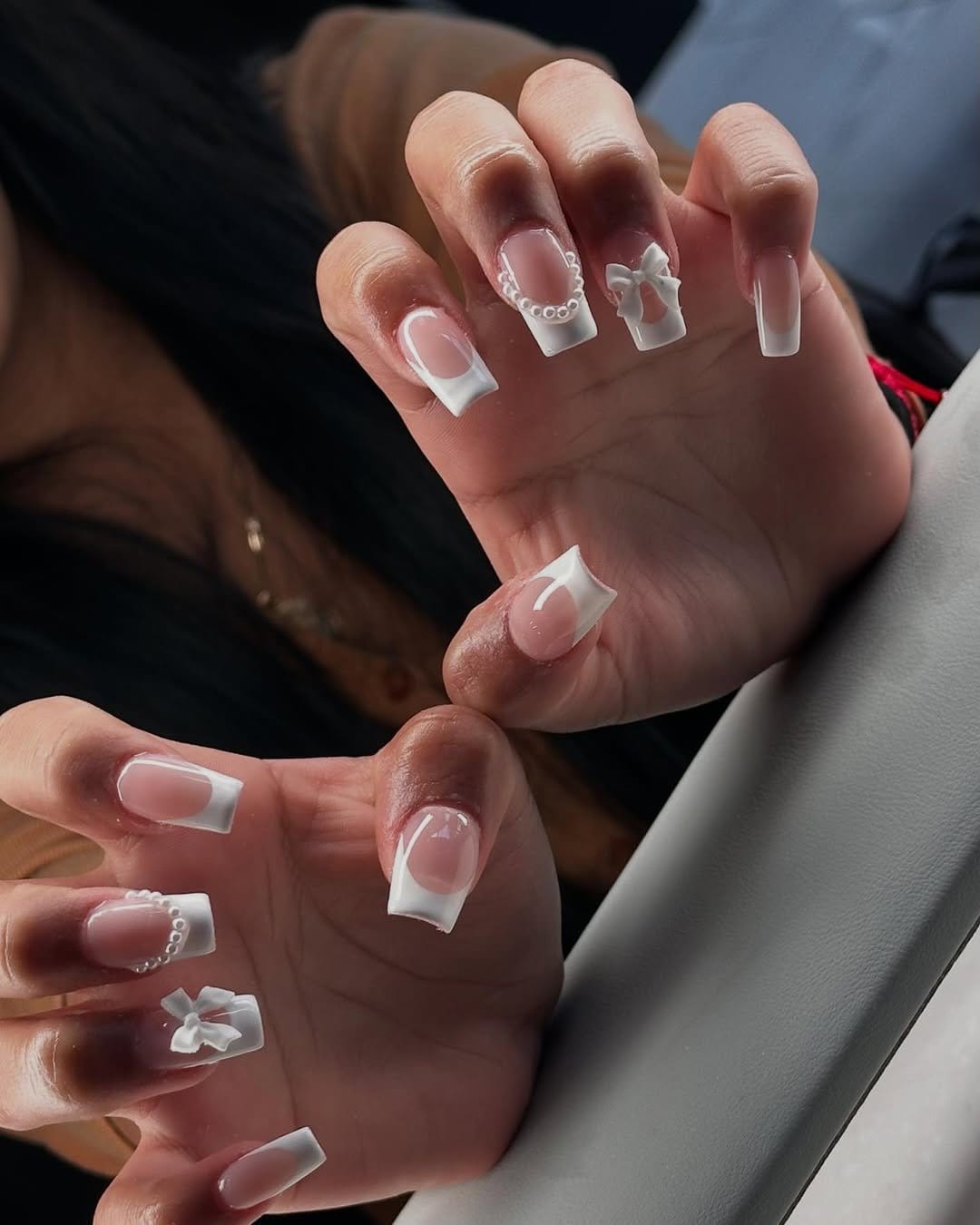 Pearl-accented French tip nails with elegant embellishments