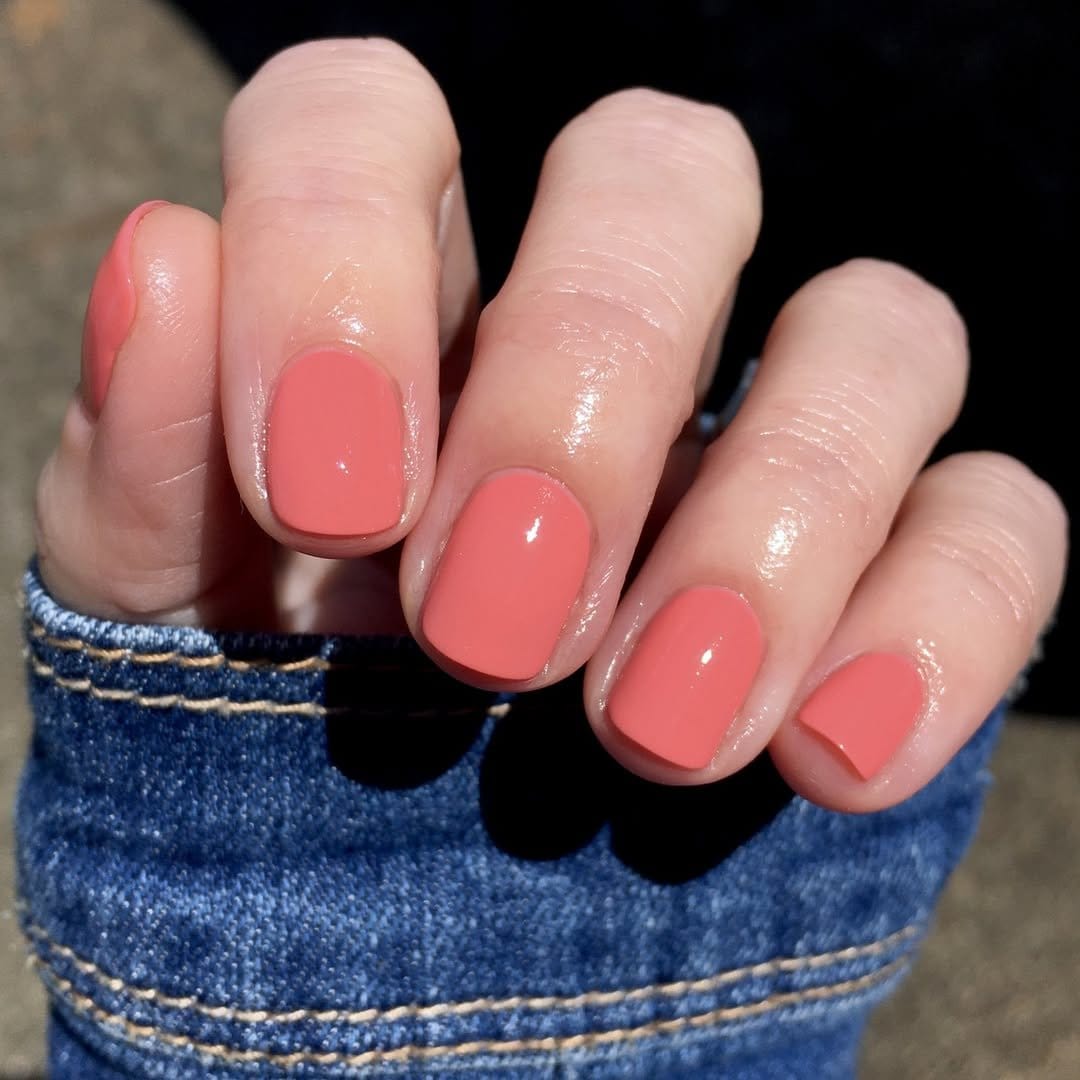 Vibrant coral nails in sunlight