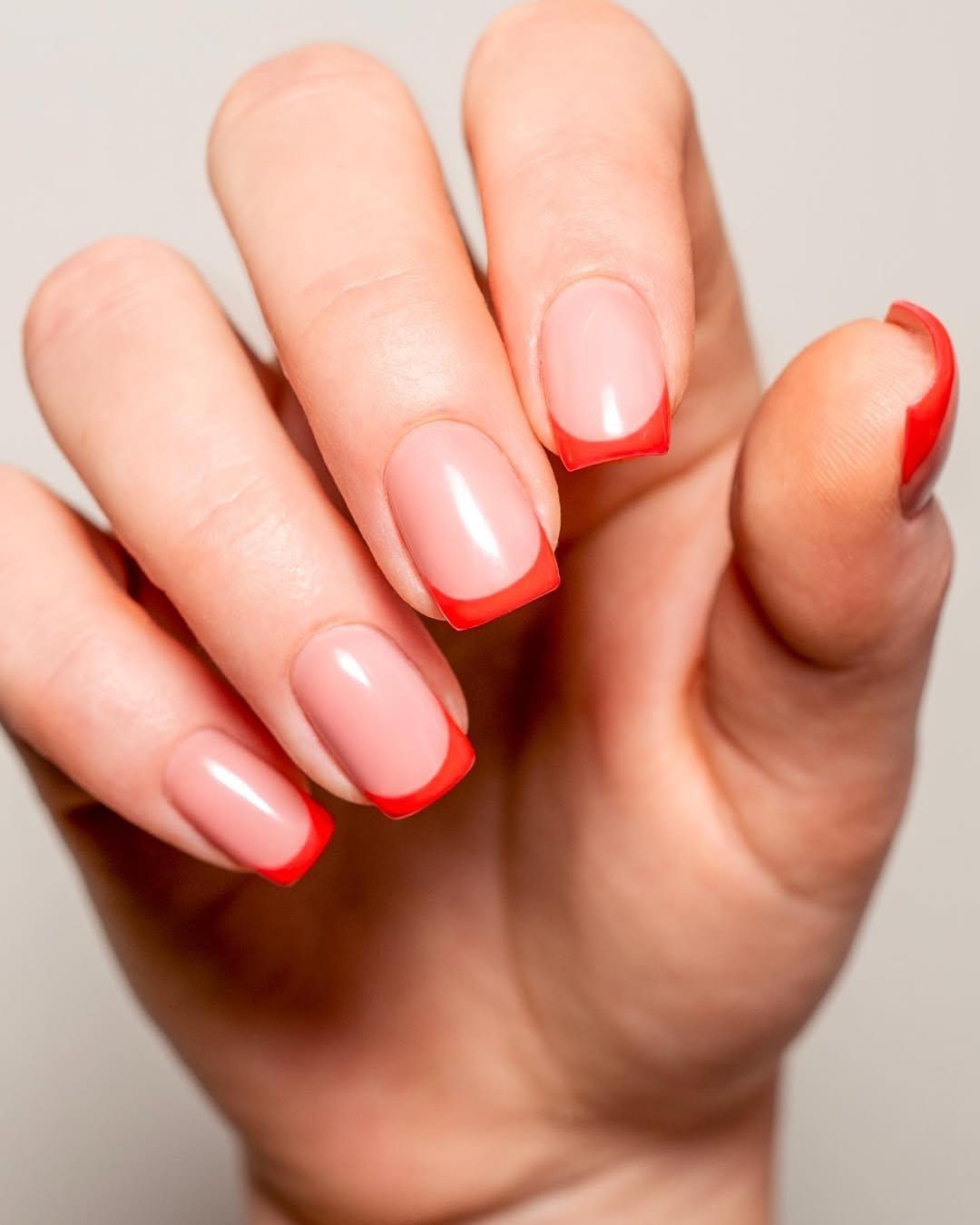 Vibrant coral French tips with glossy finish