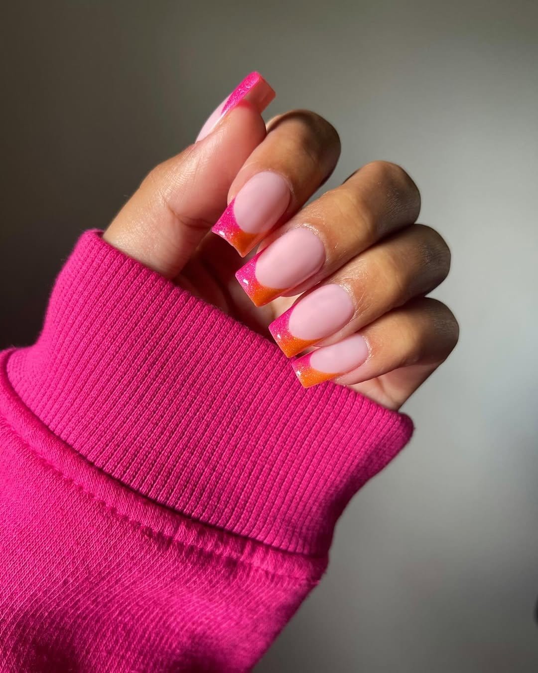 Warm sunset gradient French tips transitioning from orange to pink