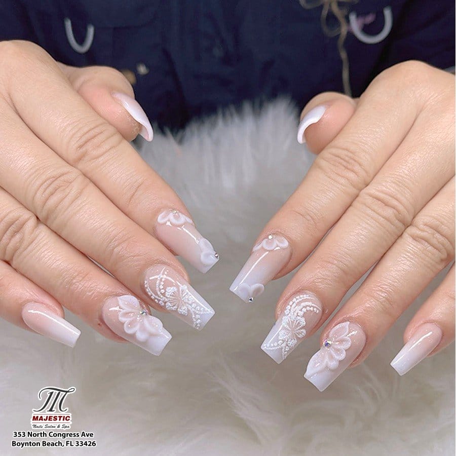 White nails adorned with lace patterns and pearls