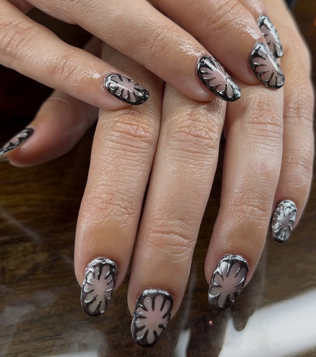 Metallic white floral nail art on dark nails